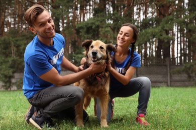 Volunteers with homeless dog at animal shelter outdoors