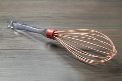 Photo of One whisk on wooden table, closeup. Kitchen tool