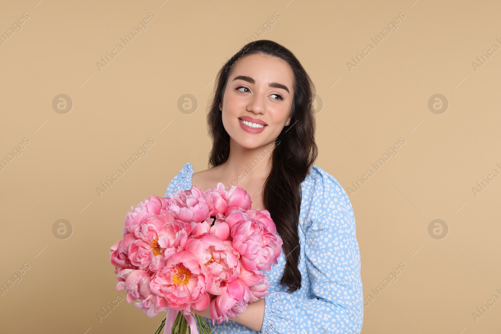 Photo of Beautiful young woman with bouquet of pink peonies on beige background