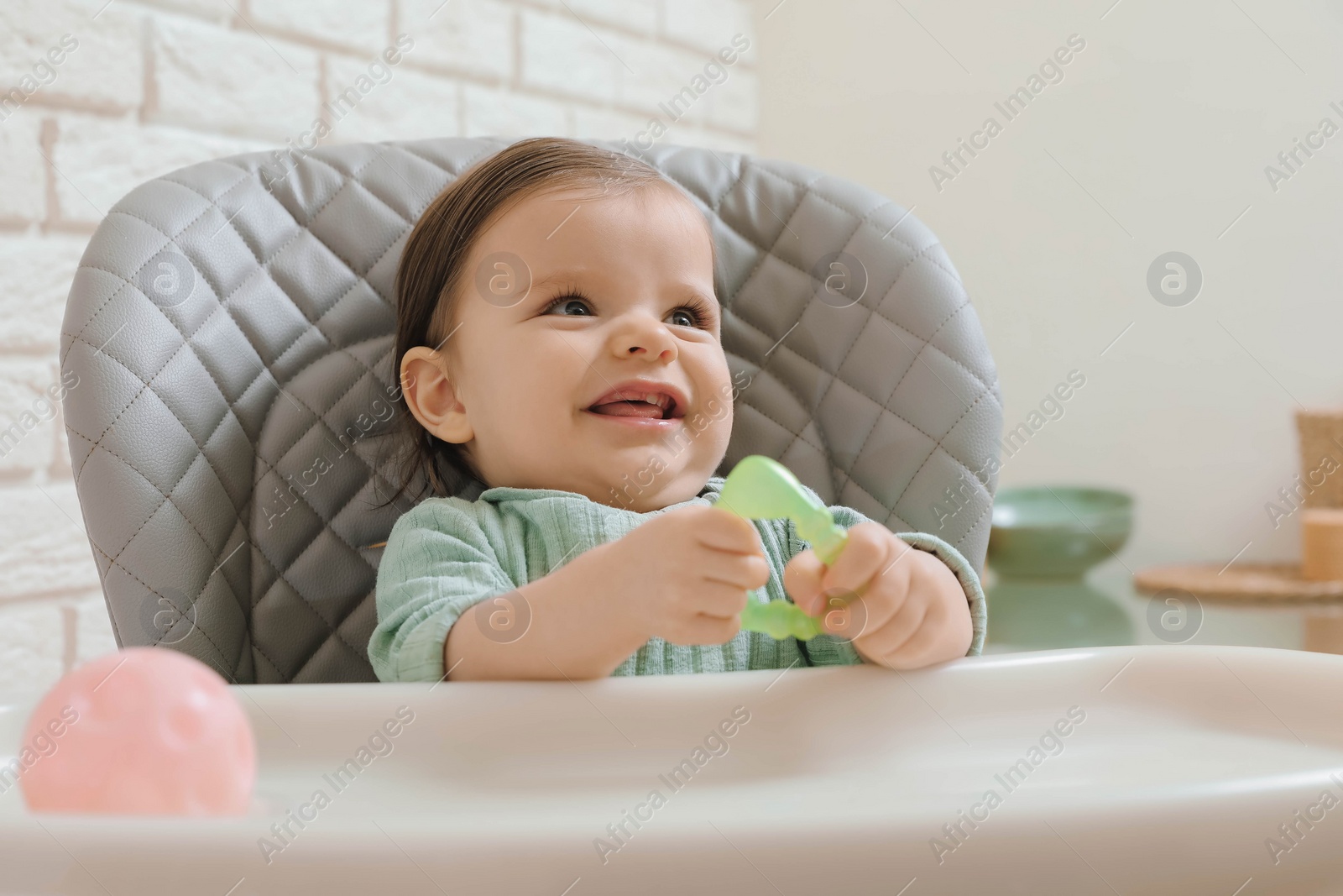 Photo of Cute little baby with teether in high chair indoors