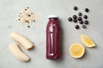 Photo of Flat lay composition with ingredients for delicious acai cocktail and bottle of juice on gray table