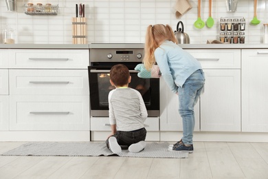 Little kids baking buns in oven at home