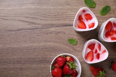 Cups of homemade yogurt and strawberries on wooden table, flat lay with space for text. Recipe for multi cooker