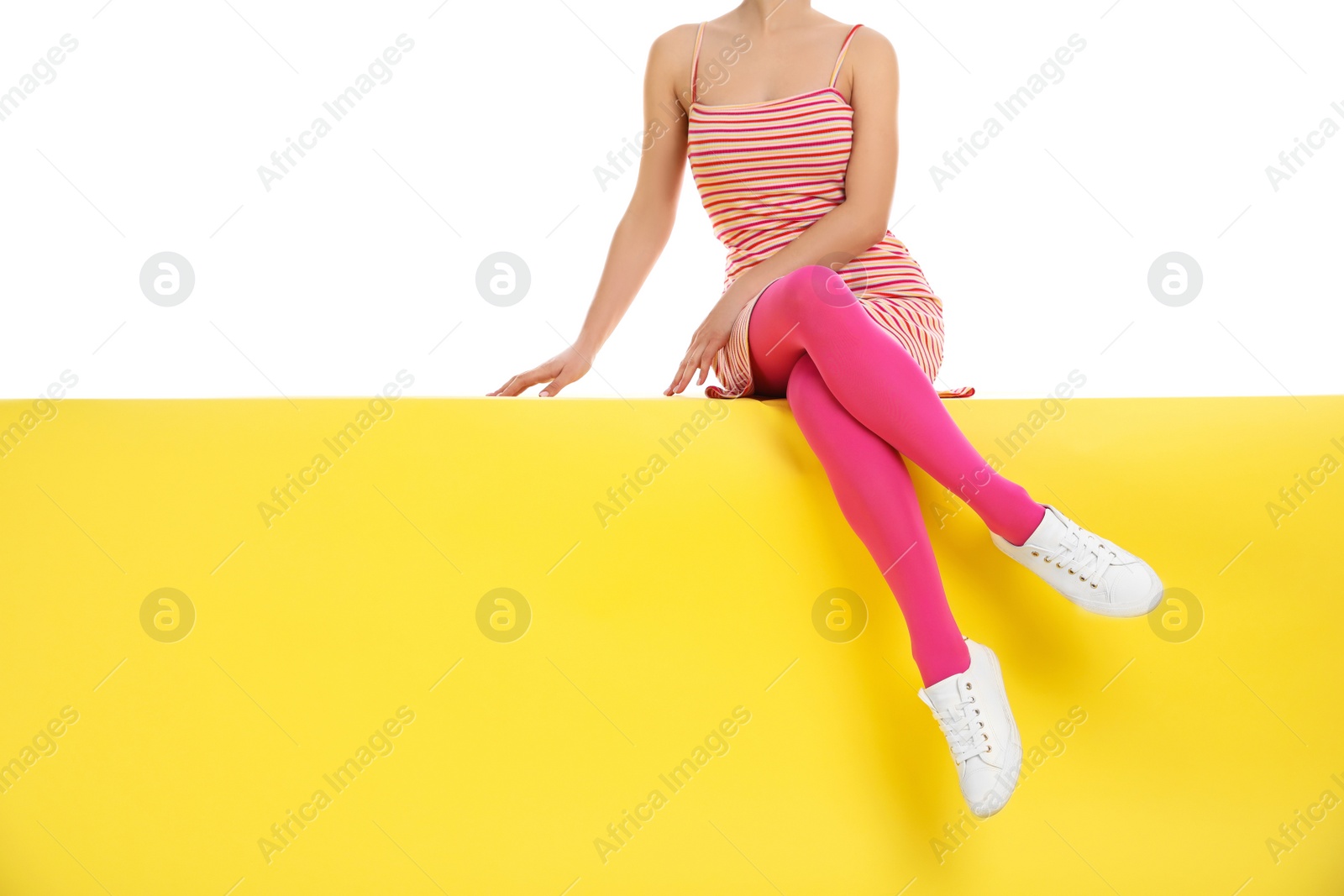 Photo of Woman wearing pink tights sitting on yellow background, closeup