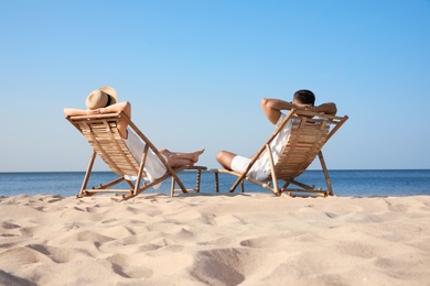 Young couple relaxing in deck chairs on beach