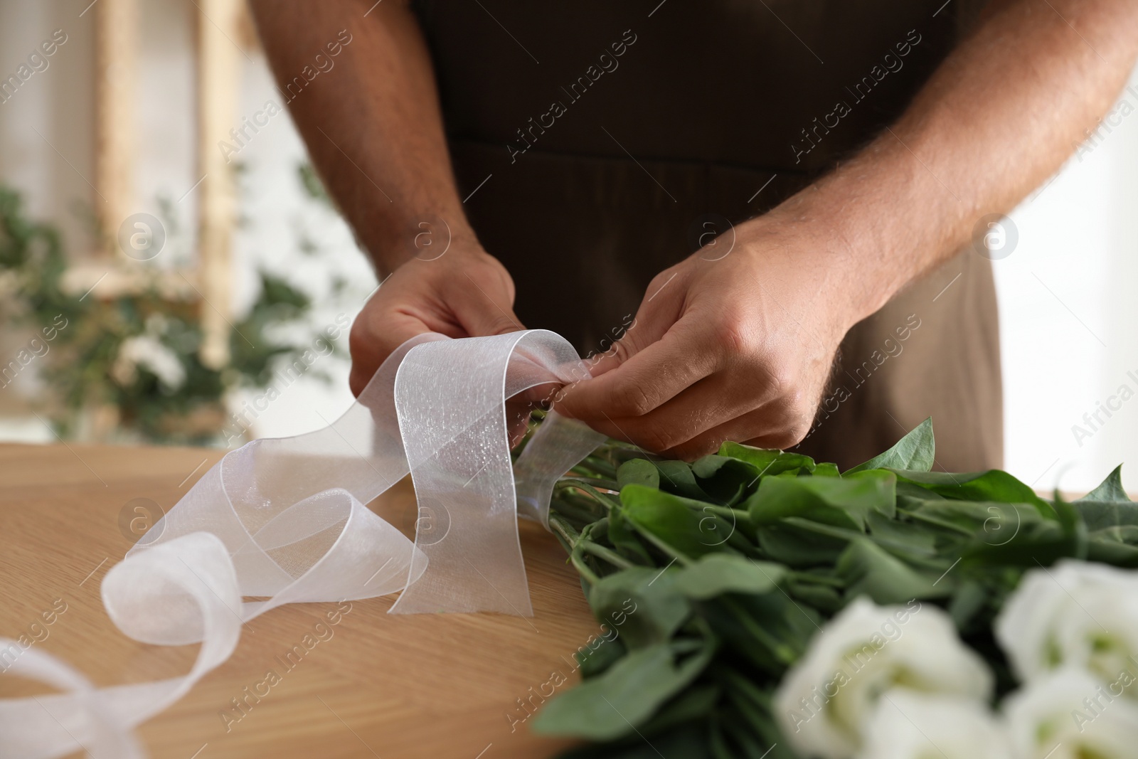 Photo of Florist making beautiful bouquet at table in workshop, closeup