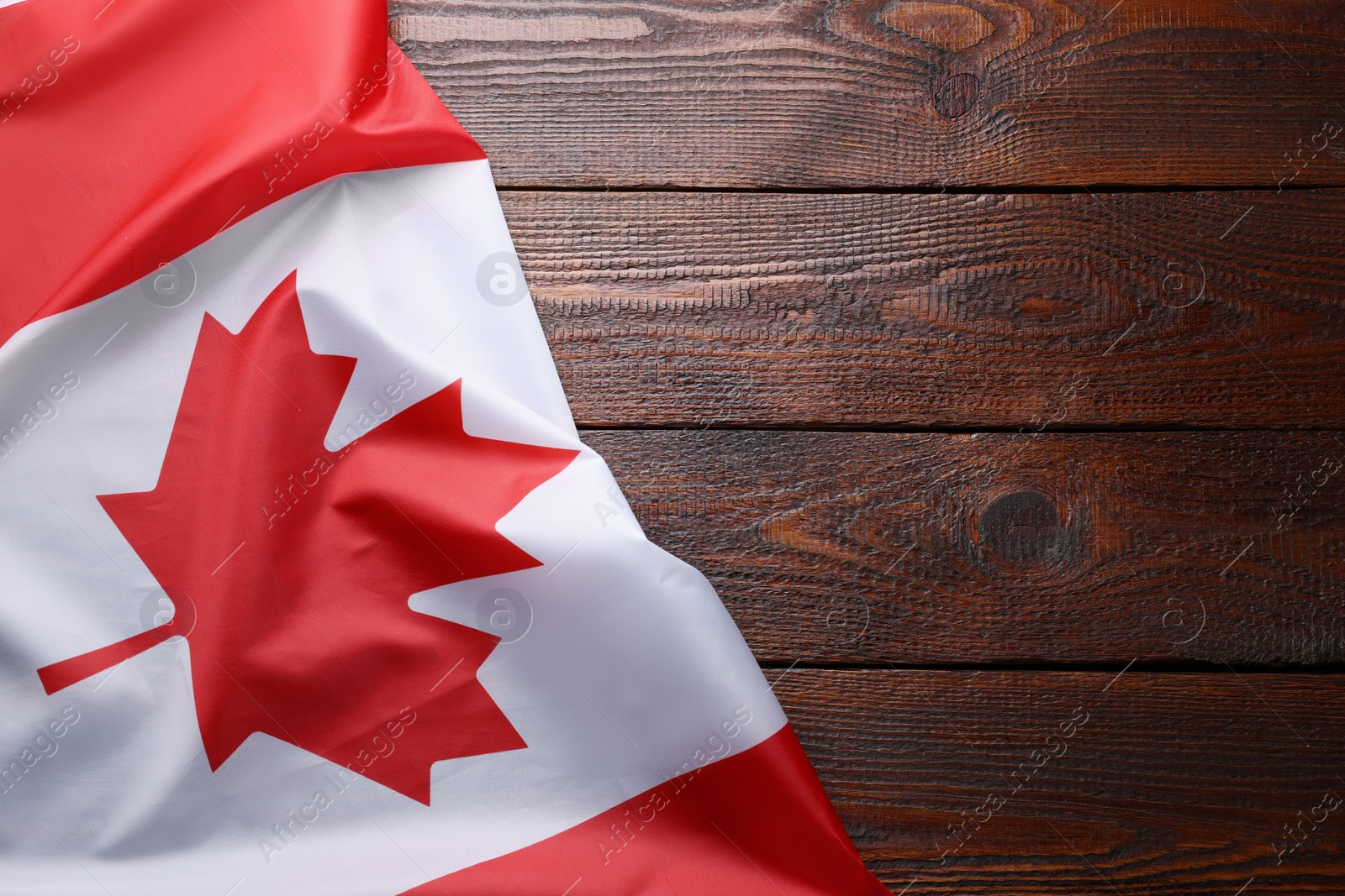 Photo of Flag of Canada on wooden table, top view. Space for text