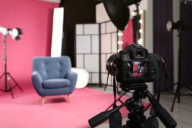 Photo of Stylish blue armchair in photo studio with professional equipment, focus on camera