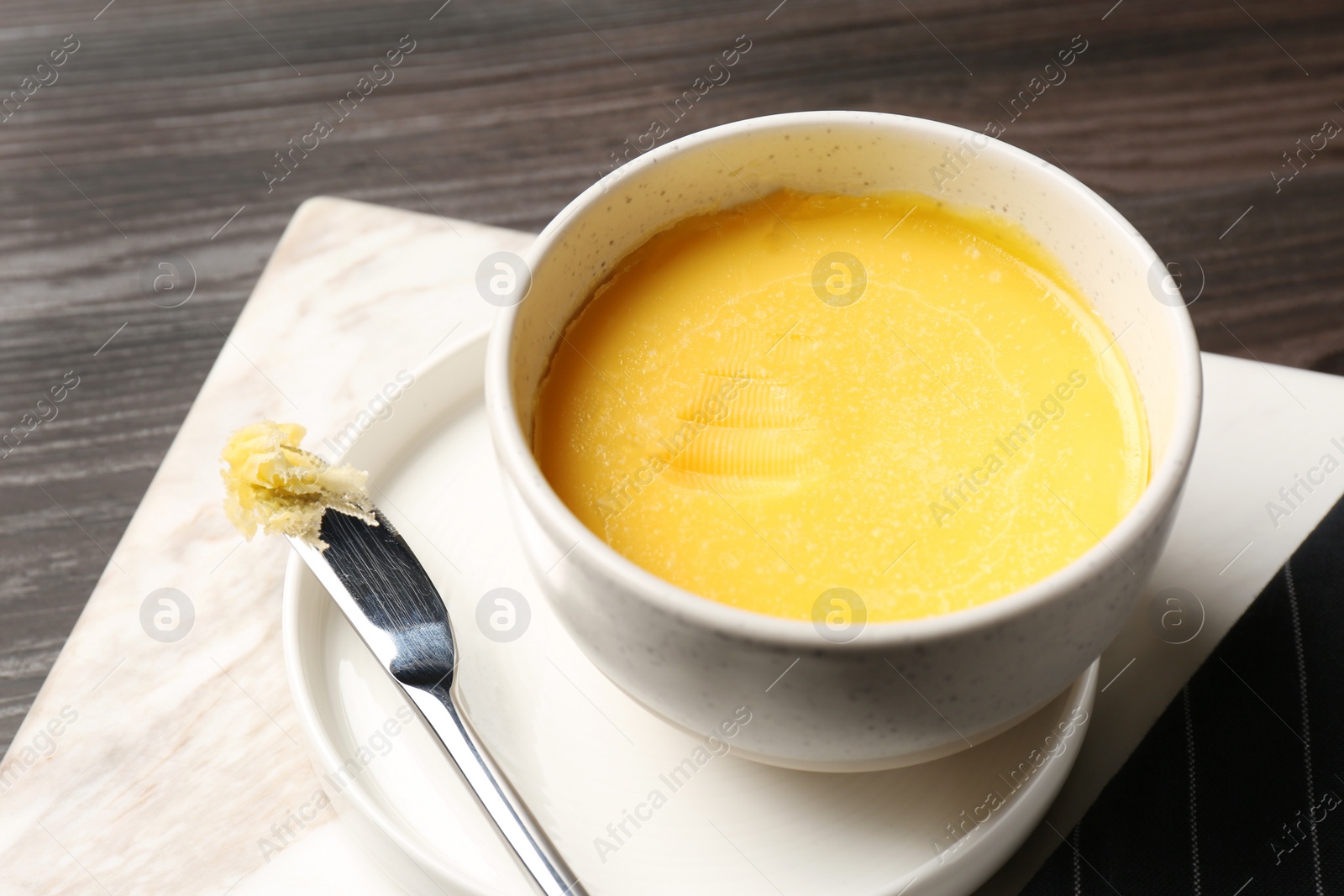 Photo of Bowl and knife with melting butter on table. Space for text