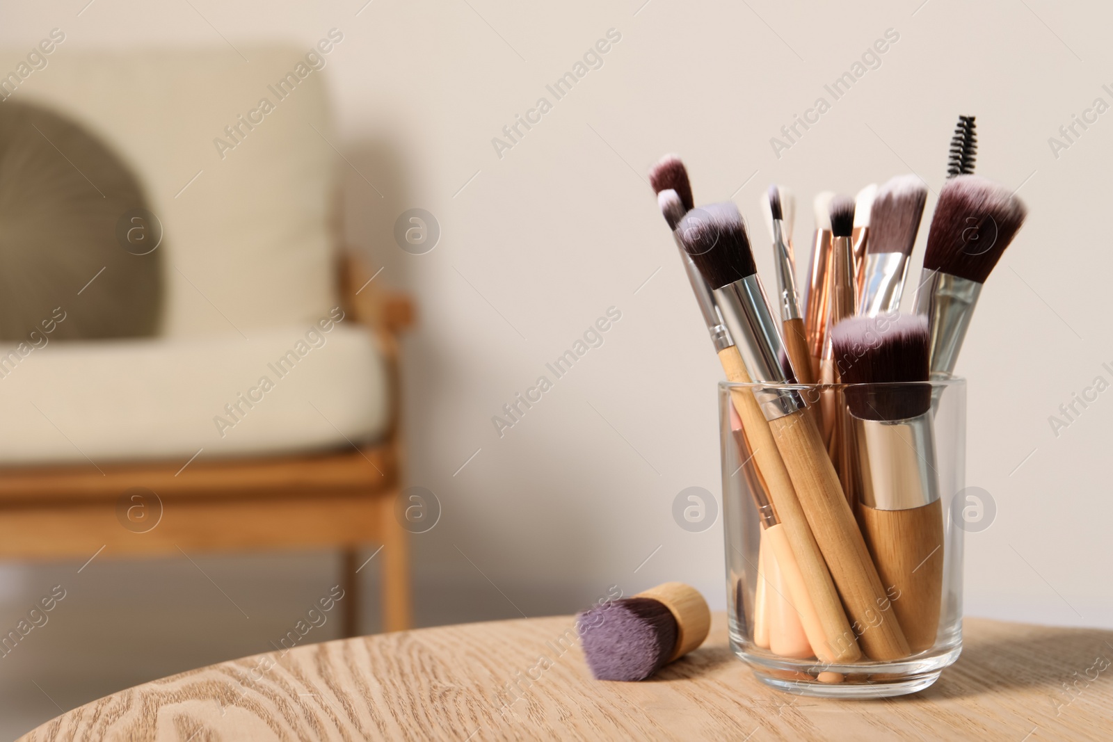 Photo of Set of professional makeup brushes on wooden table indoors, space for text