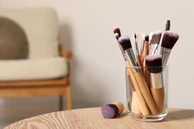 Photo of Set of professional makeup brushes on wooden table indoors, space for text