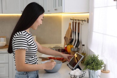 Cooking process. Woman searching recipe on tablet in kitchen