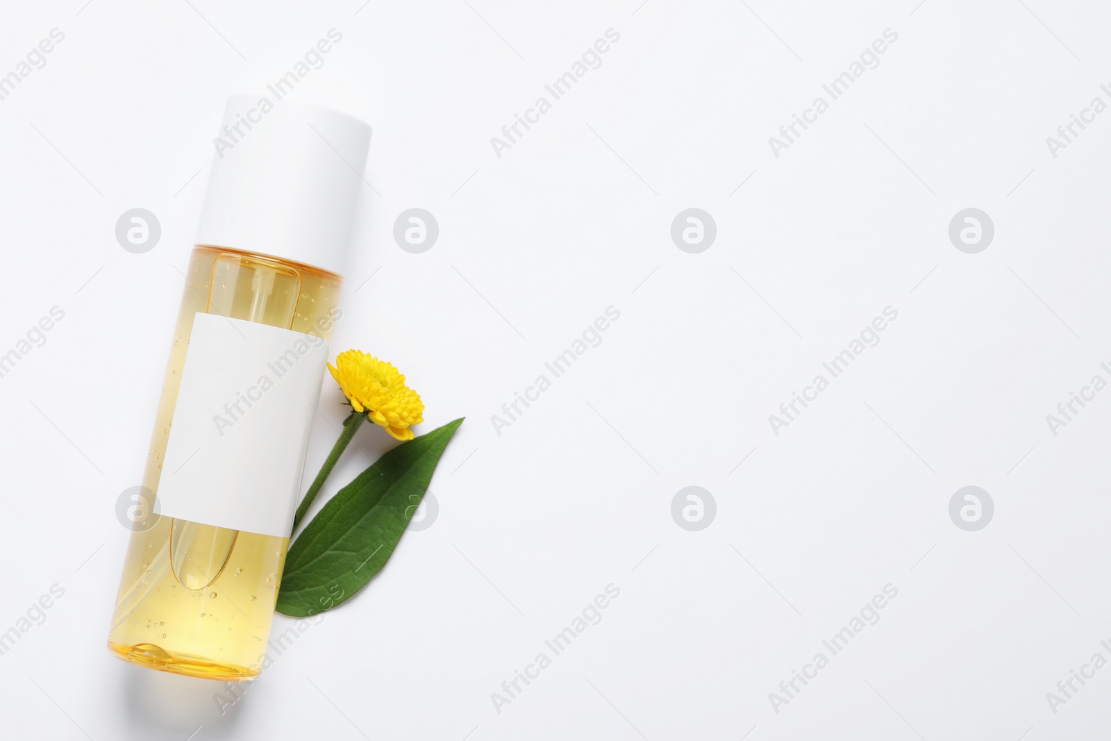 Photo of Bottle of cosmetic product and flower on white background, flat lay. Space for text