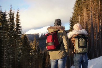 Photo of Couple with backpacks enjoying mountain view during winter vacation. Space for text