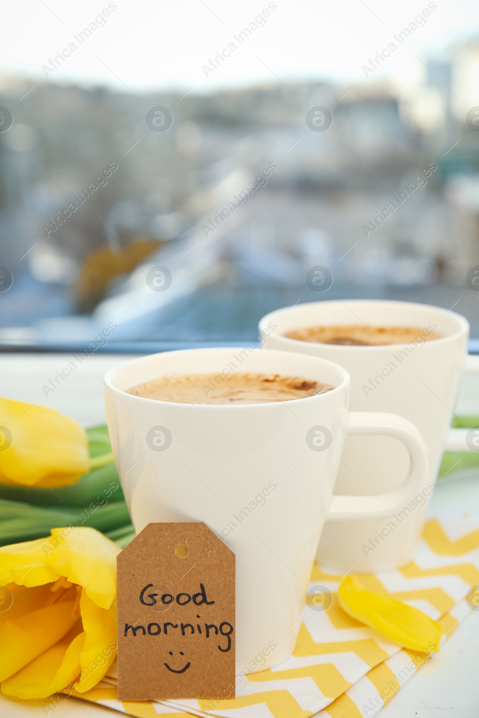 Photo of Aromatic coffee, beautiful flowers and GOOD MORNING wish on light windowsill