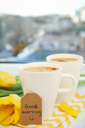 Photo of Aromatic coffee, beautiful flowers and GOOD MORNING wish on light windowsill