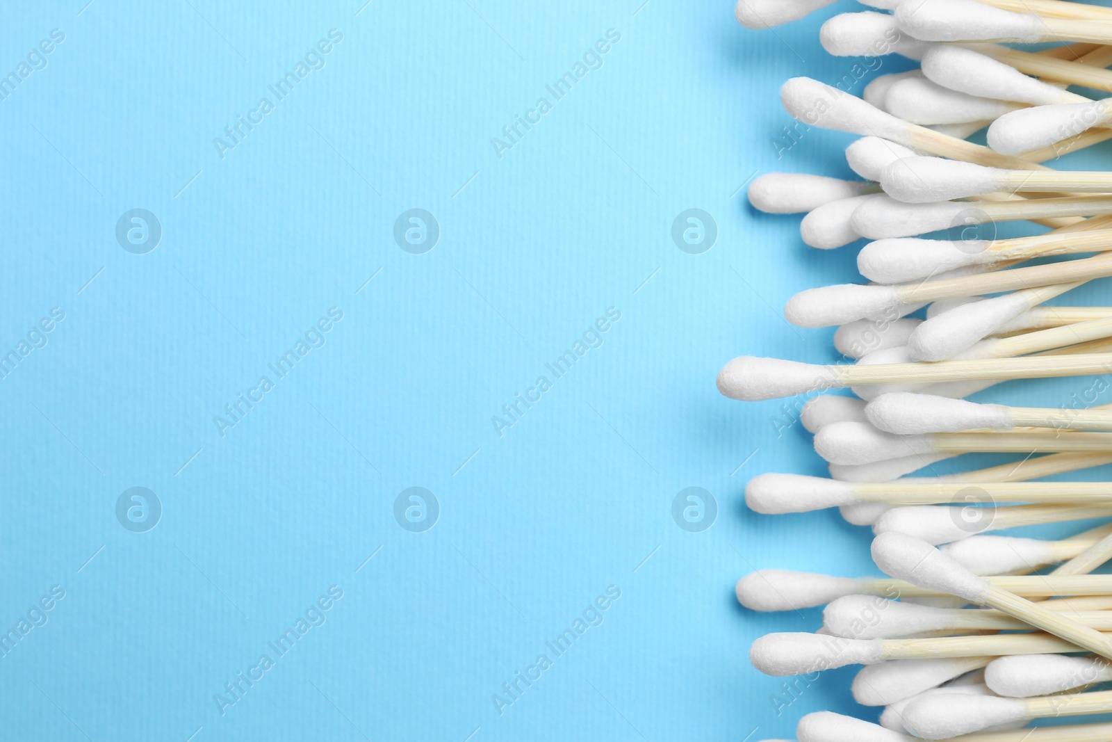 Photo of Many cotton buds on light blue background, flat lay. Space for text