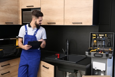 Male plumber with clipboard near kitchen sink. Repair service