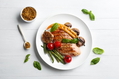 Photo of Tasty grilled chicken fillet with mustard and vegetables on white wooden table, flat lay