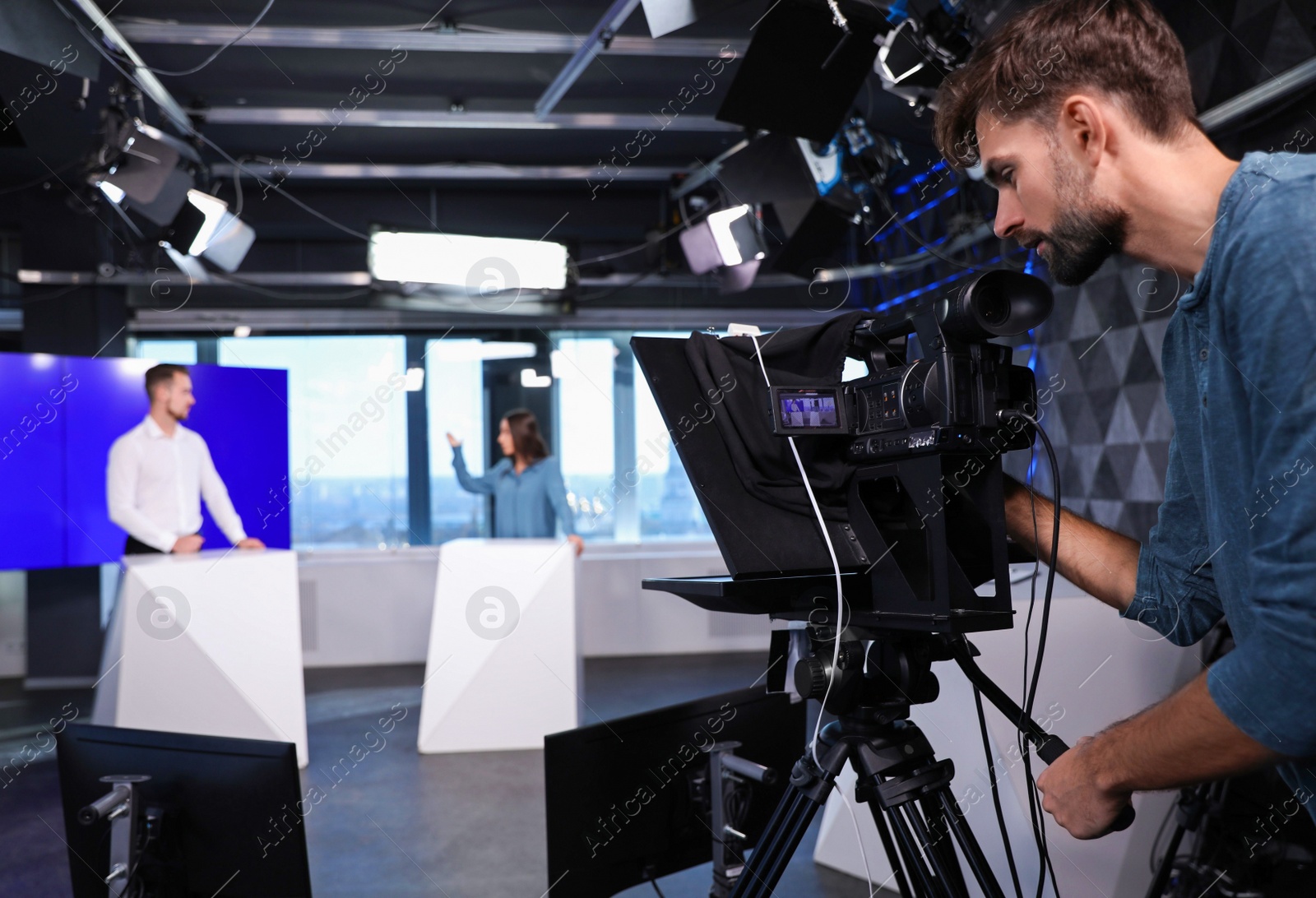 Photo of Presenters and video camera operator working in studio. News broadcasting