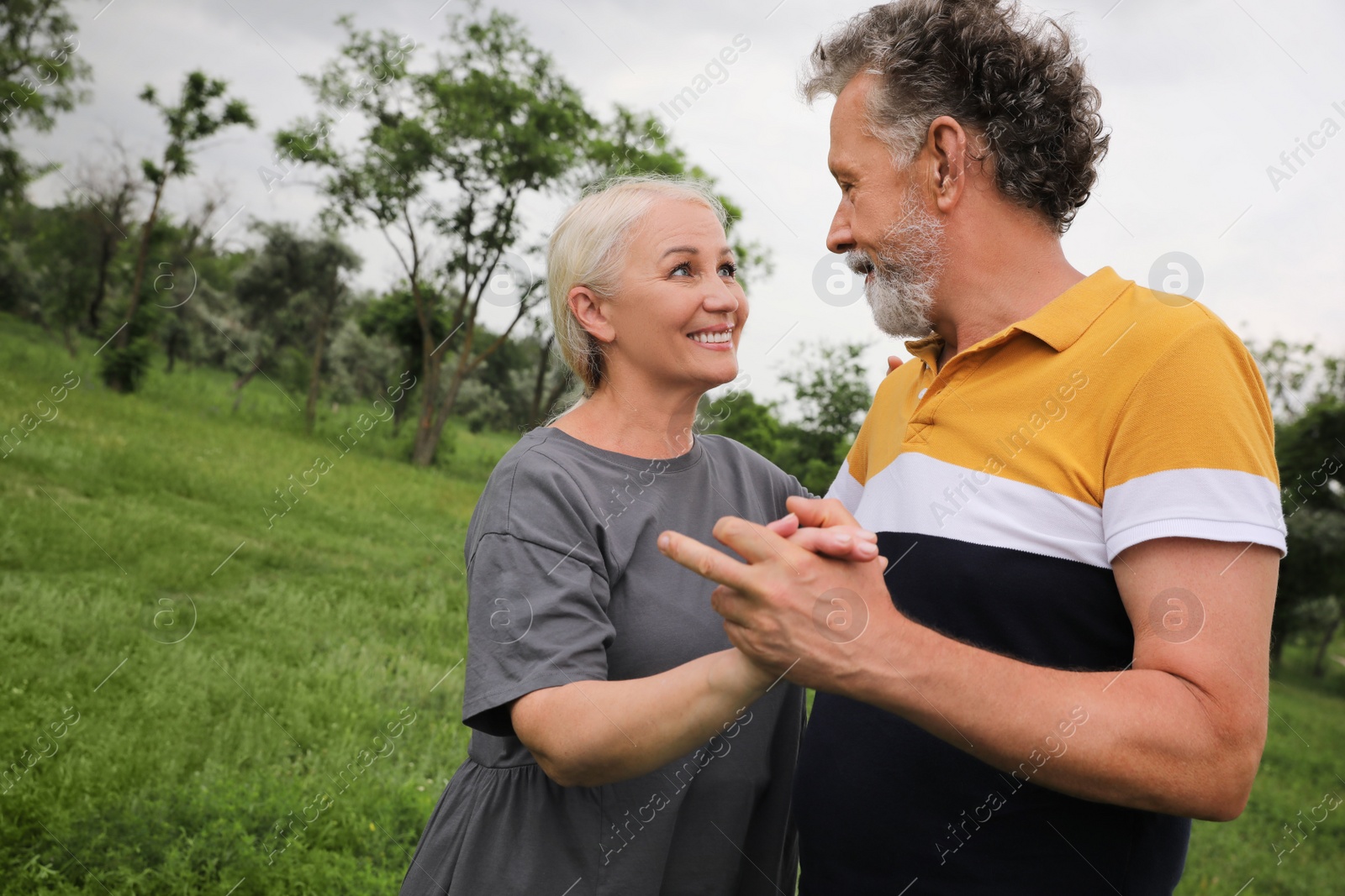 Photo of Happy mature couple dancing in park, space for text