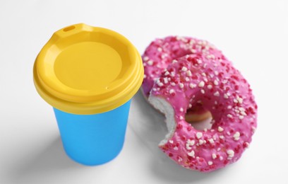 Cup of hot drink and tasty donuts on white background