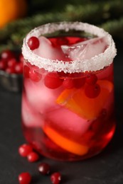 Tasty cranberry cocktail with ice cubes in glass on dark gray table, closeup