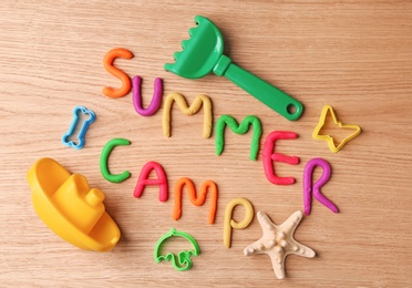 Photo of Text SUMMER CAMP made with play dough on wooden background, top view