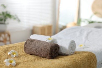 Photo of Massage table with towels and flowers in spa center, closeup