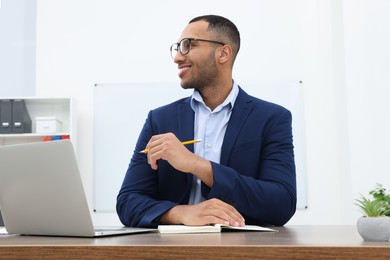 Photo of Happy young intern working at table in modern office