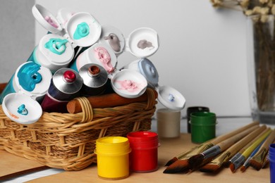 Photo of Colorful paints and brushes on wooden table