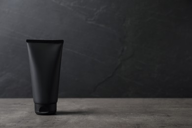 Photo of Tube of men's facial cream on grey stone table. Mockup for design