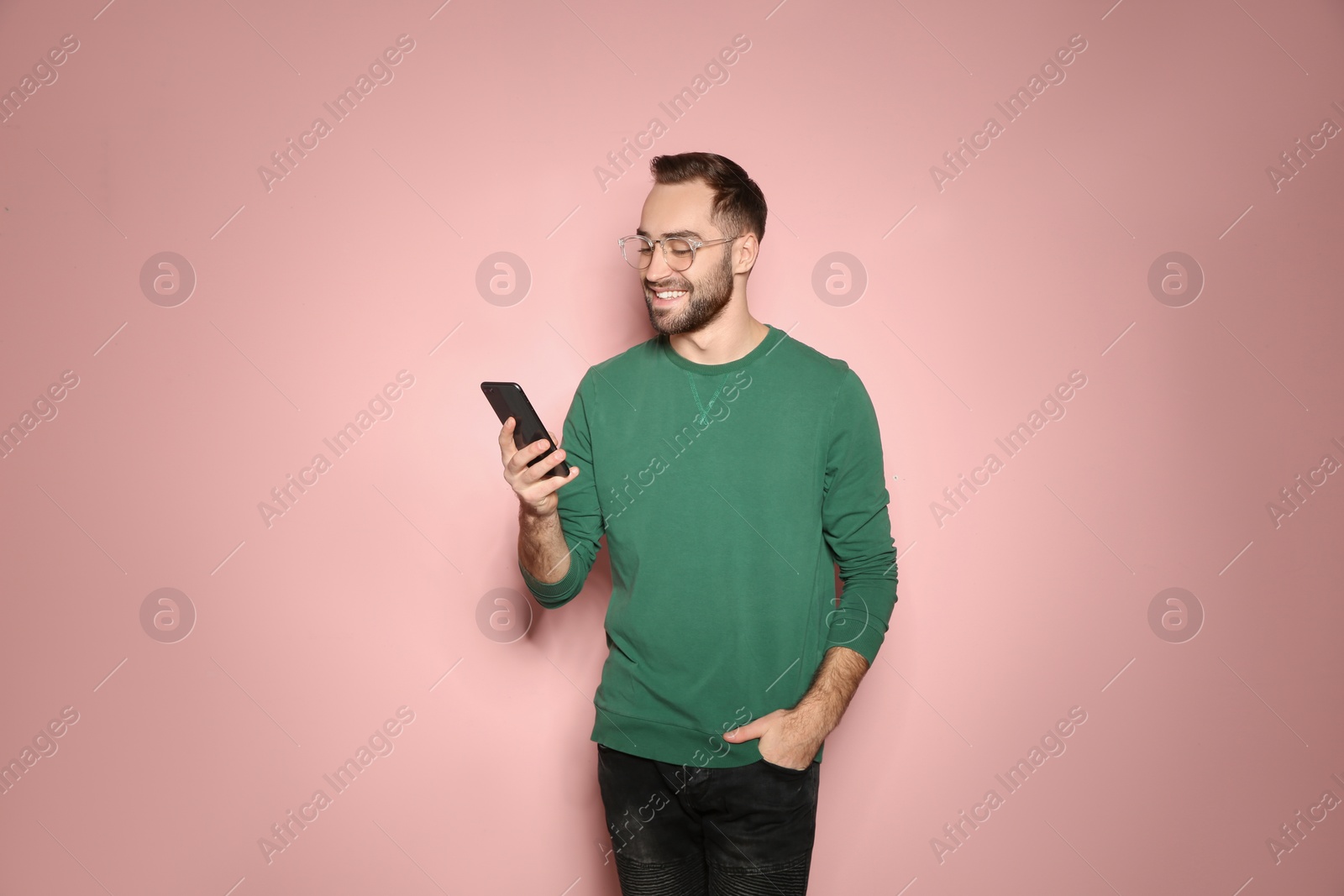 Photo of Handsome young man with mobile phone on color background