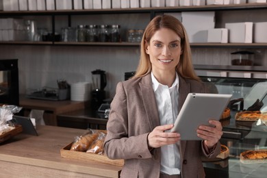 Photo of Happy business owner with tablet in bakery shop. Space for text
