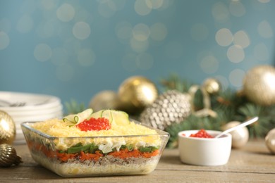 Photo of Traditional russian salad Mimosa and festive decor on table against blurred lights