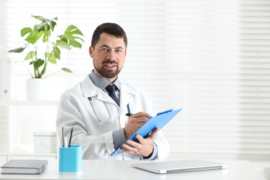 Portrait of male doctor in white coat at workplace