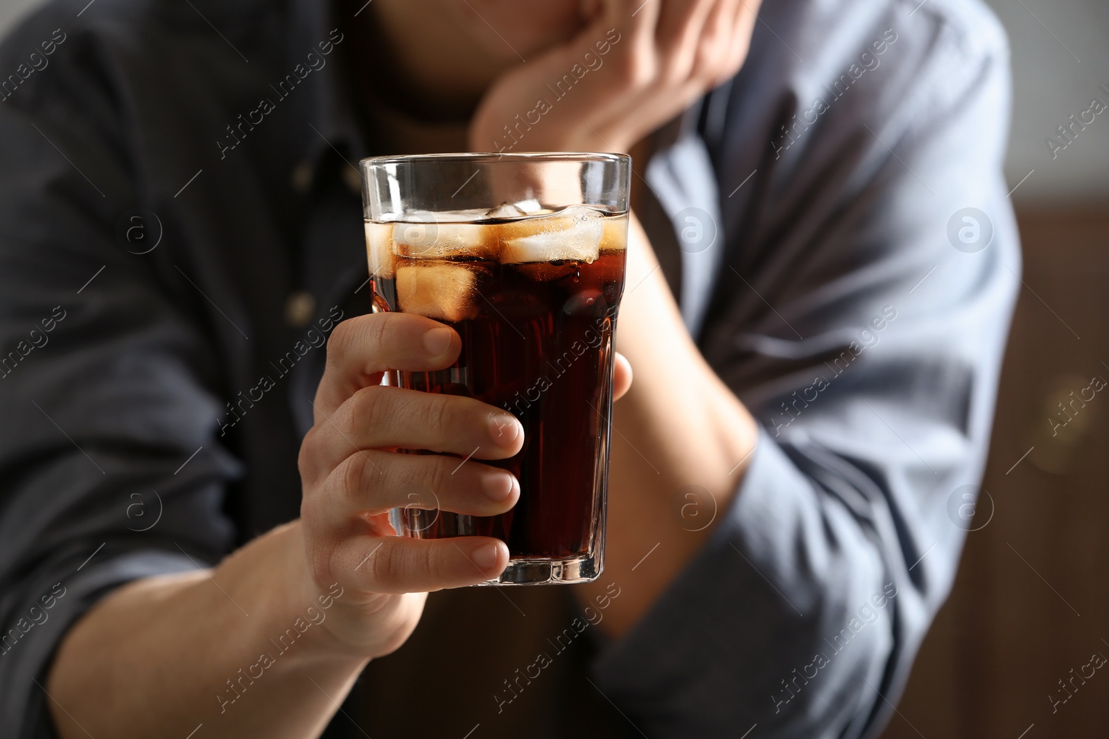 Photo of Man with glass of cold cola indoors, closeup