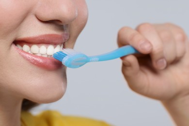 Photo of Woman brushing her teeth with plastic toothbrush on white background, closeup