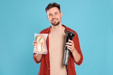 Photo of Smiling man holding sous vide cooker and salmon in vacuum pack on light blue background