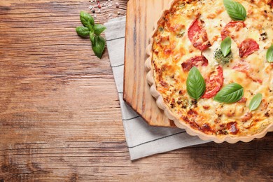 Photo of Tasty quiche with tomatoes, basil and cheese on wooden table, flat lay. Space for text