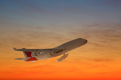 Airplane flying in sky at sunset. Air transportation