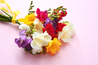 Beautiful freesia bouquet with ribbon on color background