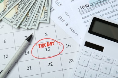 Photo of Calendar with date reminder about tax day, documents, pen, calculator and money, top view