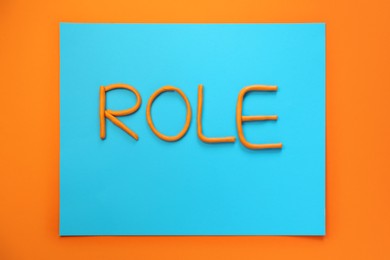 Photo of Word Role made with plasticine on orange background, flat lay