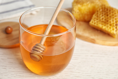 Photo of Glass jar of honey on white wooden table, closeup