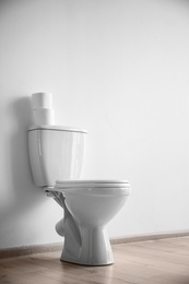 Photo of New ceramic toilet bowl near light wall