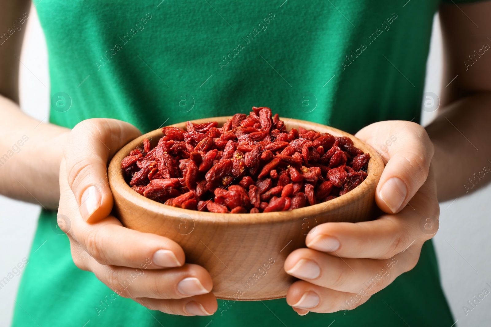 Photo of Woman holding bowl of red dried goji berries, closeup