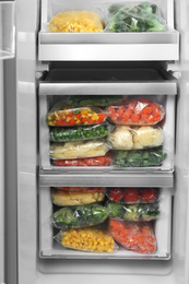 Photo of Plastic bags with different frozen vegetables in refrigerator