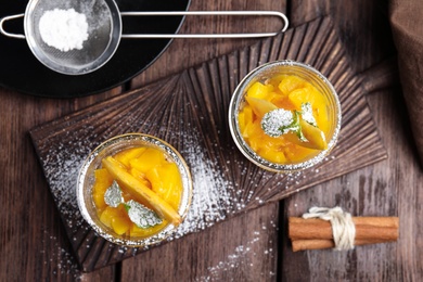 Photo of Tasty peach dessert served on wooden table, flat lay