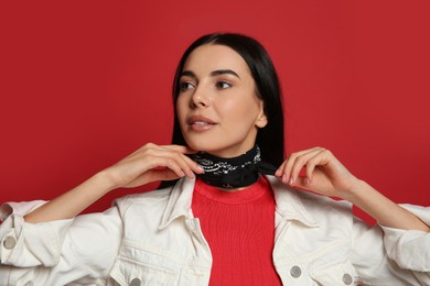 Photo of Fashionable young woman in stylish outfit with bandana on red background